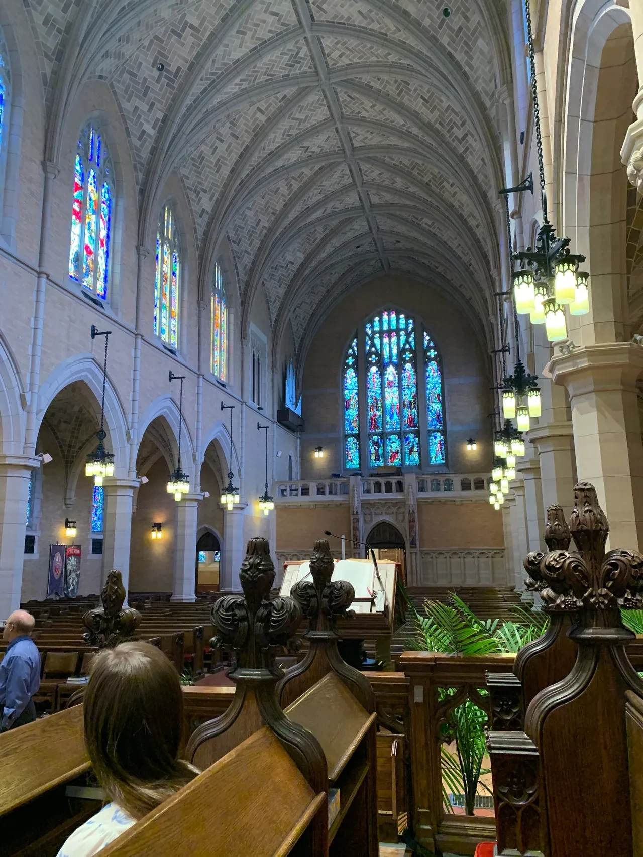 Gothic nave interior with stained glass windows and carved wooden pews