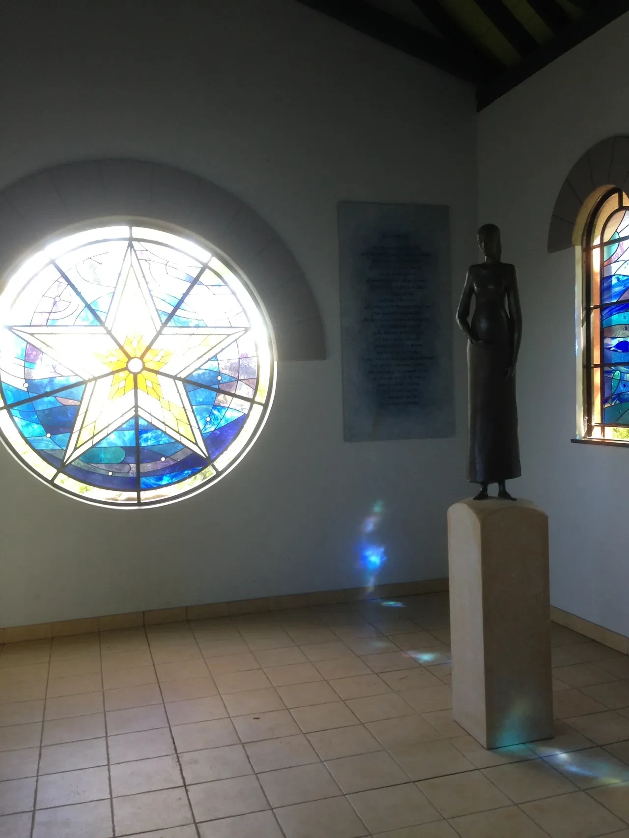 Chapel interior with star-shaped stained glass window and bronze statue